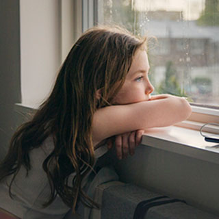 female child gazing out a window